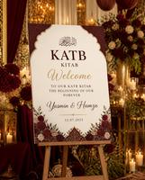 Burgundy Cream Katb Kitab welcome board displayed on an easel